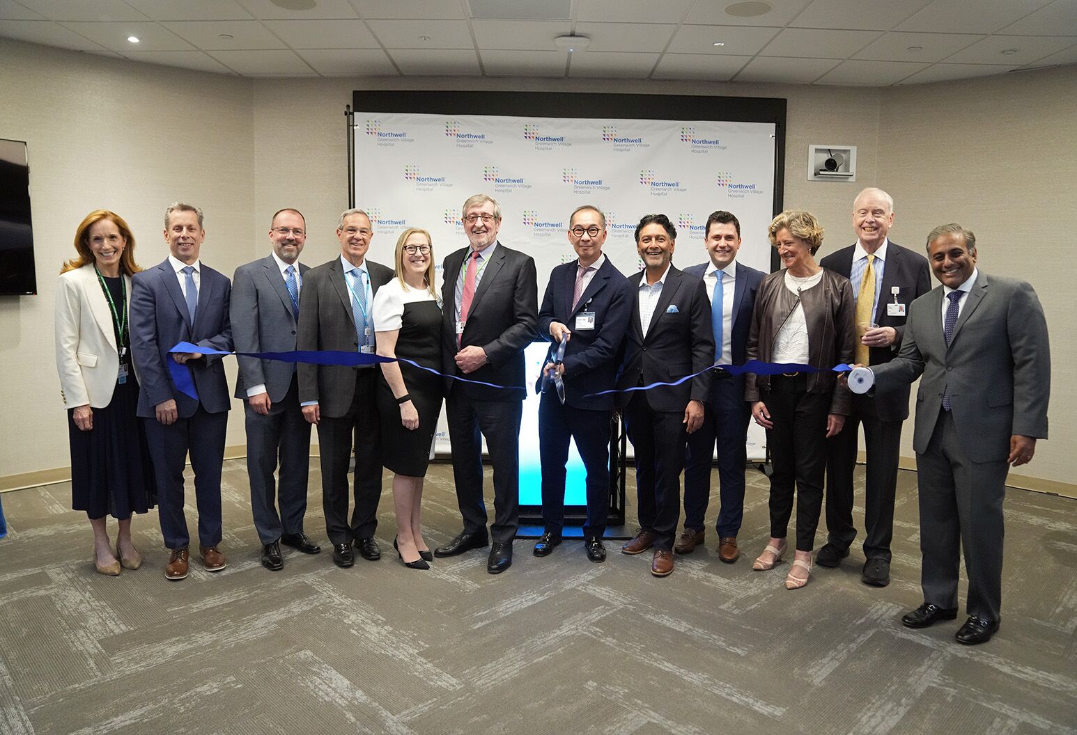 A group of people in business attire standing on a carpet in front of a Northwell Health branded screen